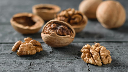 Ripe walnuts split and scattered on a dark wooden table.