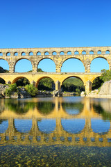 Aqueduct Pont du Gard reflected in Gardon River, southern France
