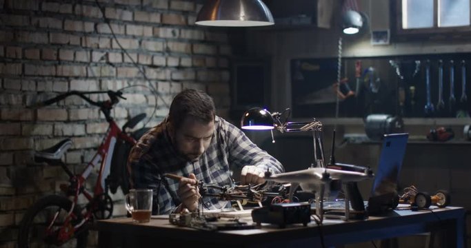 Medium shot of a man repairing and testing a drone in a garage
