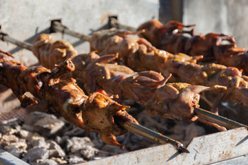 grilling quails over charcoal stove