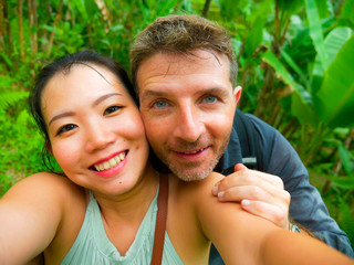 Fototapeta premium young beautiful and happy mixed ethnicity couple beautiful Asian Chinese woman and white man in love taking selfie picture outdoors enjoying romantic holidays trip