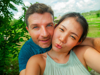 Fototapeta premium young beautiful and happy mixed ethnicity couple beautiful Korean Chinese woman and white man in love taking selfie picture outdoors enjoying romantic holidays trip