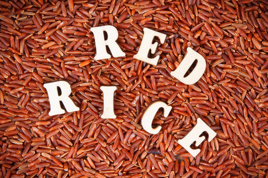 Heap of red rice with inscription as background, healthy gluten free food concept