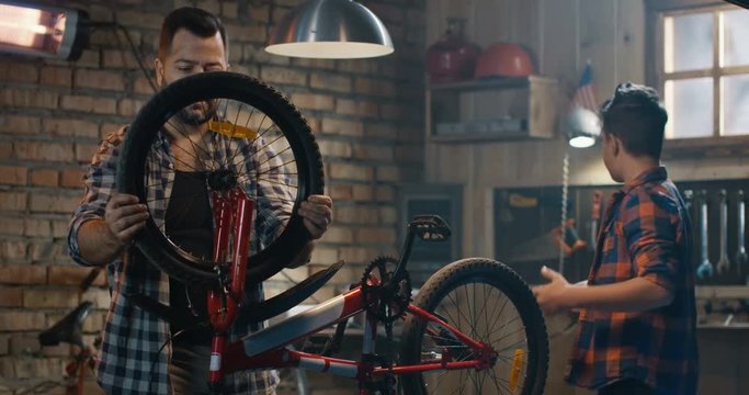 Medium shot of father and son repairing a bike in a garage