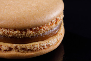 Bright juicy delicious macarons of almond color on a black background.