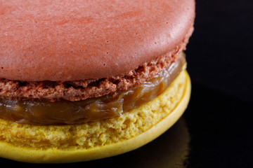 Bright juicy delicious macarons of two colors on a black background.