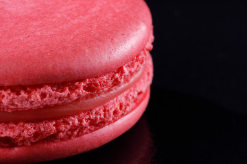 Bright juicy delicious macarons pink color on a black background.