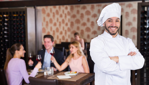 Confident smiling chef standing in restaurant hall