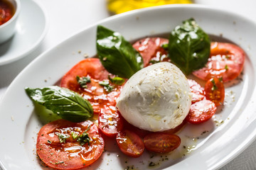 Caprese salad from mozzarella tomatoes basil olive oil an spices