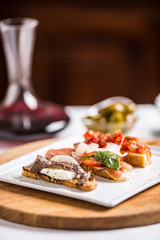 Tasty italian appetizer bruschettes with tomatoes anchovies prosciutto and mozarella