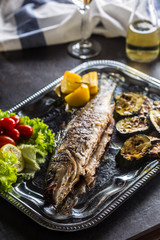 Roasted fish on dish with fresh and grilled vegetable