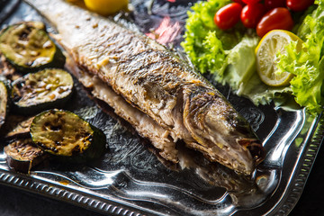 Roasted fish on dish with fresh and grilled vegetable