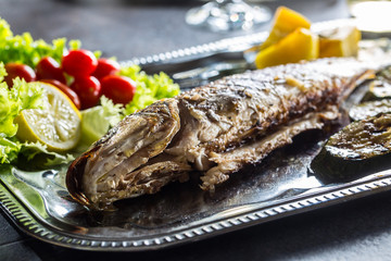Roasted fish on dish with fresh and grilled vegetable