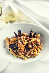 Italian pasta with mussels and prawn in white plate