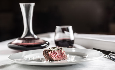 Beef tenderloin steak on white plate and red wine in pub or restaurant