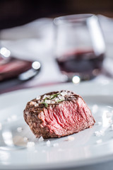 Beef tenderloin steak on white plate and red wine in pub or restaurant