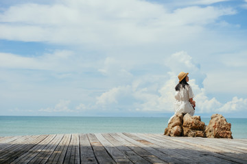 Obraz premium single Asian girl looks aside sitting on rock at tropical resort, Ao Nang, Krabi, Thailand.