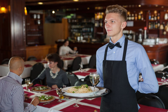 Waiter with tray in restaurant
