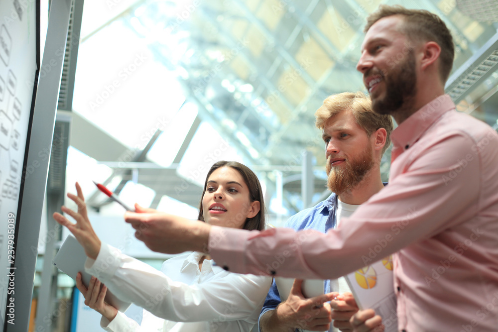 Wall mural Casual business people working with whiteboard in office.