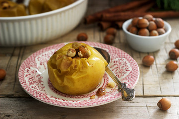 Baked apples with raisins, hazelnuts and cinnamon on wooden background. Rustic style.