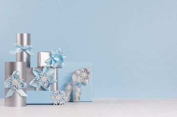 Festive christmas various snowy gift boxes in light blue pastel color with silver ribbons on white wood table.