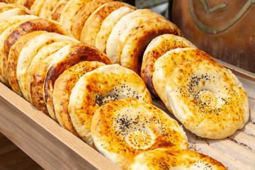 Close-up of tandyr bread cakes freshly baked appetizingly laid out in even rows on the counter of a shopping center in the bakery section. Natural products in the store.