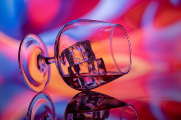 Overturned the brandy glass on a bright colored background