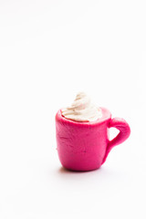 Obraz premium Miniature play dough coffee or latte cup with cream topping, piece of cake on pink plate, white isolated background, artificial food concept, kids craft sculpture, mini art, copy space, coffee shop