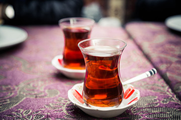 Turkish or Azerbaijani tea in pear shape glasses with saucers on ethnic national table cloth, traditional eastern hot black tea for Ramadan or Novruz, copy space