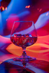 Glass of cognac with ice on a bright background
