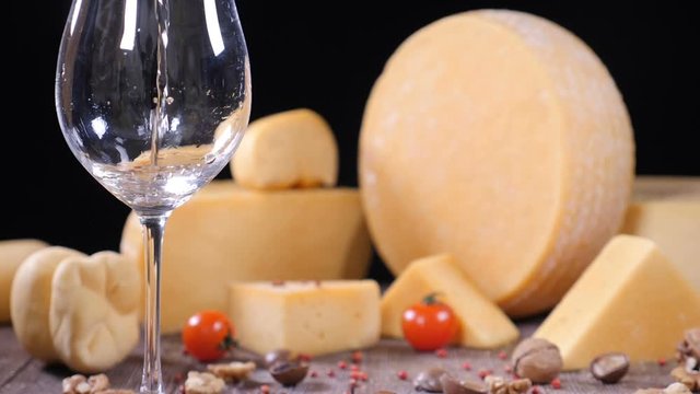 White wine is poured into a glass with a varieyty of hard cheese on background. Food art concept. Restaurant serving. Catering concept. Holidays festive concept. hd