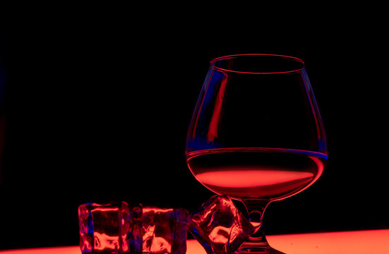 Glass of cognac with ice on a black background