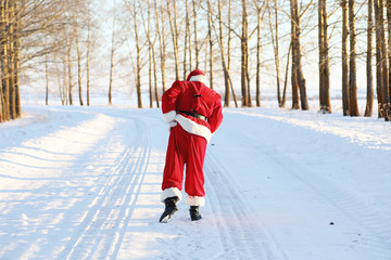 Santa in the winter field. Santa magical fog is walking along the field. Santa on Christmas Eve is carrying presents to children in a red bag.