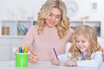 Beautiful mother with daughter drawing with colorful pencils