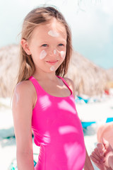 Father applying sun cream to daughter nose.