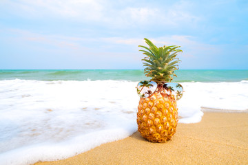 Hipster pineapple with sunglasses on a sandy beach. concept of fashion in summer. vintage color tone filter effect