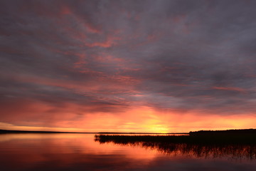 Obraz premium Summertime the twilight sky in bright colors of sunlight on the lake water surface