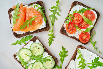 Smorrebrod - traditional Danish sandwiches. Black rye bread with salmon, cream cheese, cucumber,...