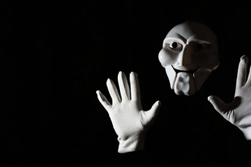 White scary mask on a black background with whites hand.