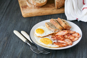 Fried eggs with chicken ham and bread on a plate