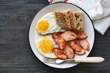 Fried eggs with chicken ham and bread on a plate