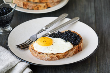 Sandwich with fried egg and caviar on a plate