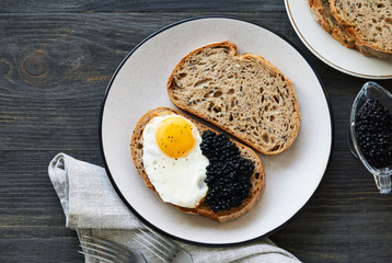 Sandwich with fried egg and caviar on a plate