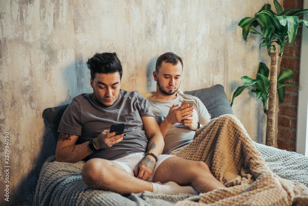 Wall mural Two homosexual male friends enjoy resting together, have positive expressions, make selfie photo, share pictures in social networks.