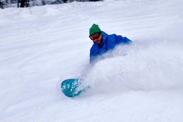 Professional snowboarder in bright sportswear and outfit skiing downhill in snowy sunny high...