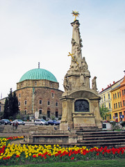 Obraz premium Szechenyi Square in Pecs with mosque-church museum and holy trinity statue, Southern Hungary