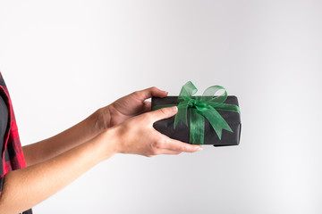 Female hands holding black paper gift box decorated with green ribbon