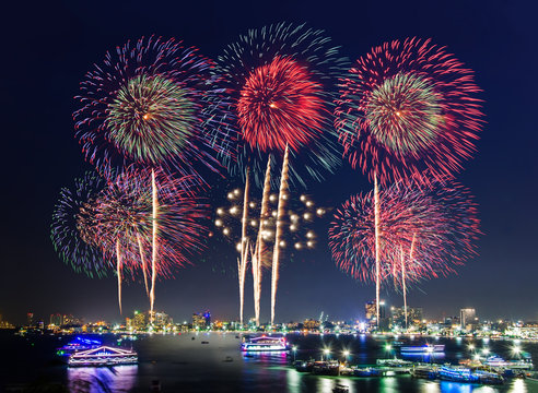 Fireworks over cityscape by the beach and sea surrounding with hotels, restaurant, and service boats and cruises during blue twilight time for celebrating New Year eve and special occasion on holidays