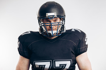 Handsome caucasian man wearing black american football uniform and helmet over white background