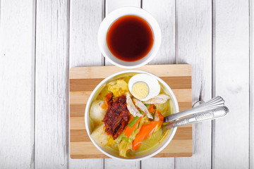 Lontong-Traditional Malaysian and   Indonesian food on wooden table with spoon.